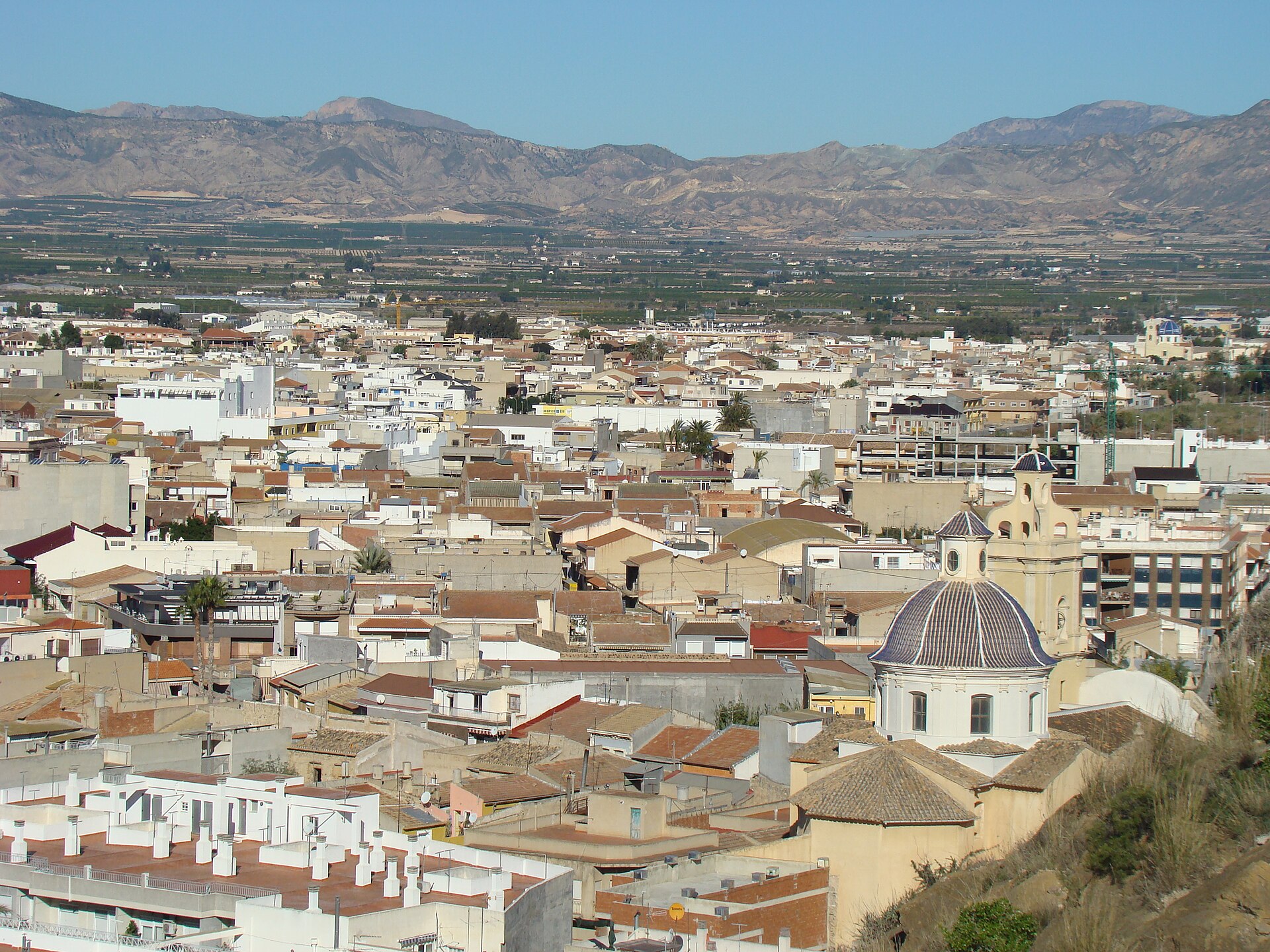Panorámica de la huerta y el casco urbano de Cox con montañas al fondo