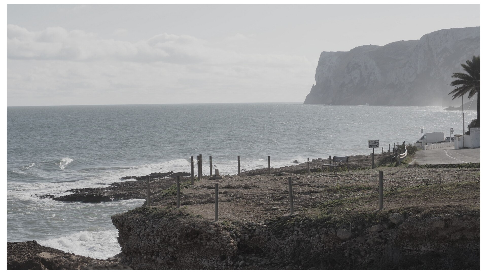 Final de les Rotes a Dénia amb camí, banc i palmera a la vora del mar.