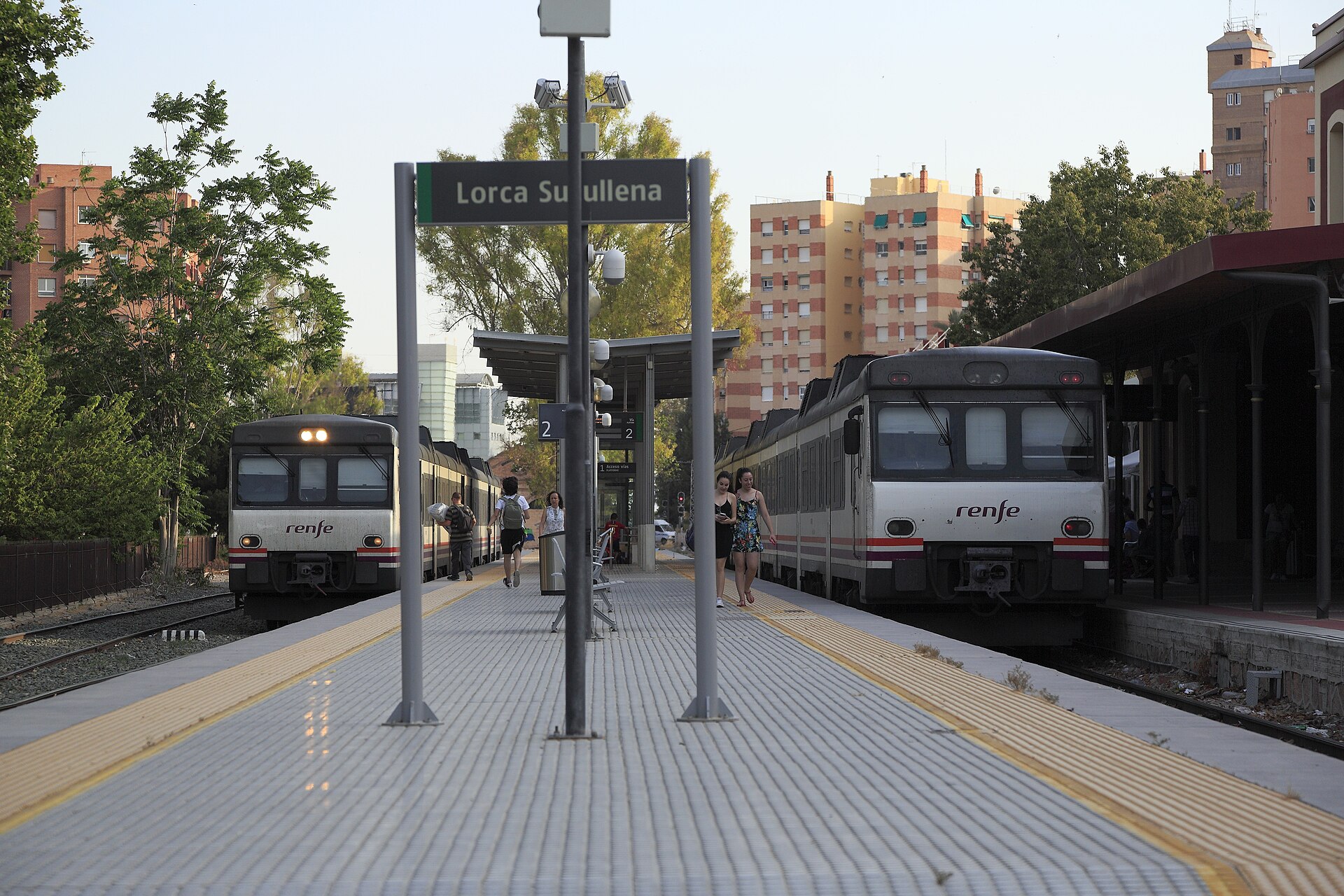 Andén de la estación Lorca-Sutullena con letrero y trenes