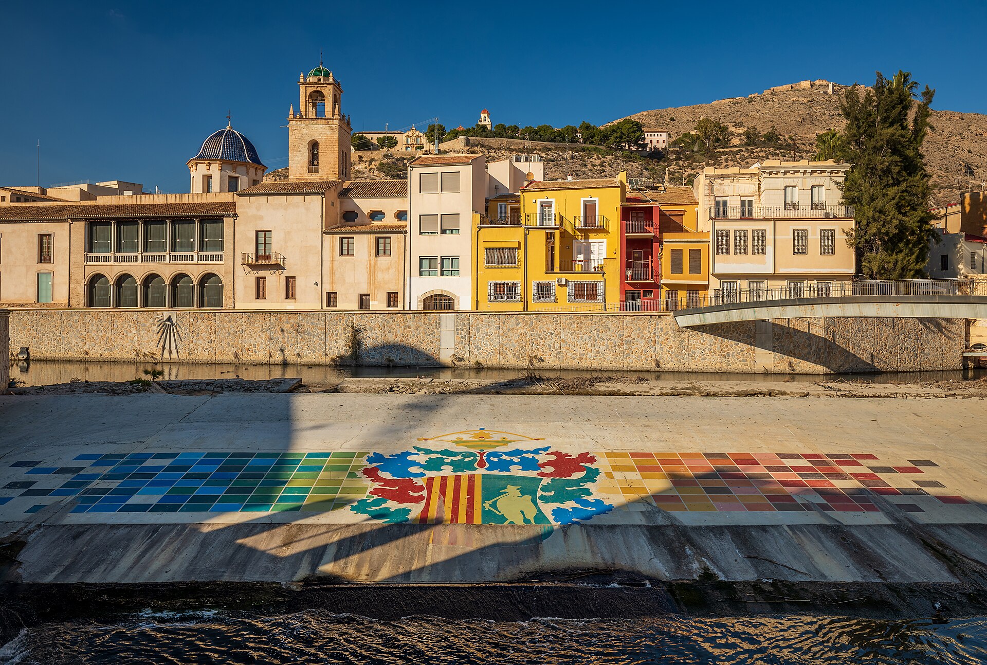 Estructura del azud y escudo pintado sobre el cauce del río Segura en Orihuela
