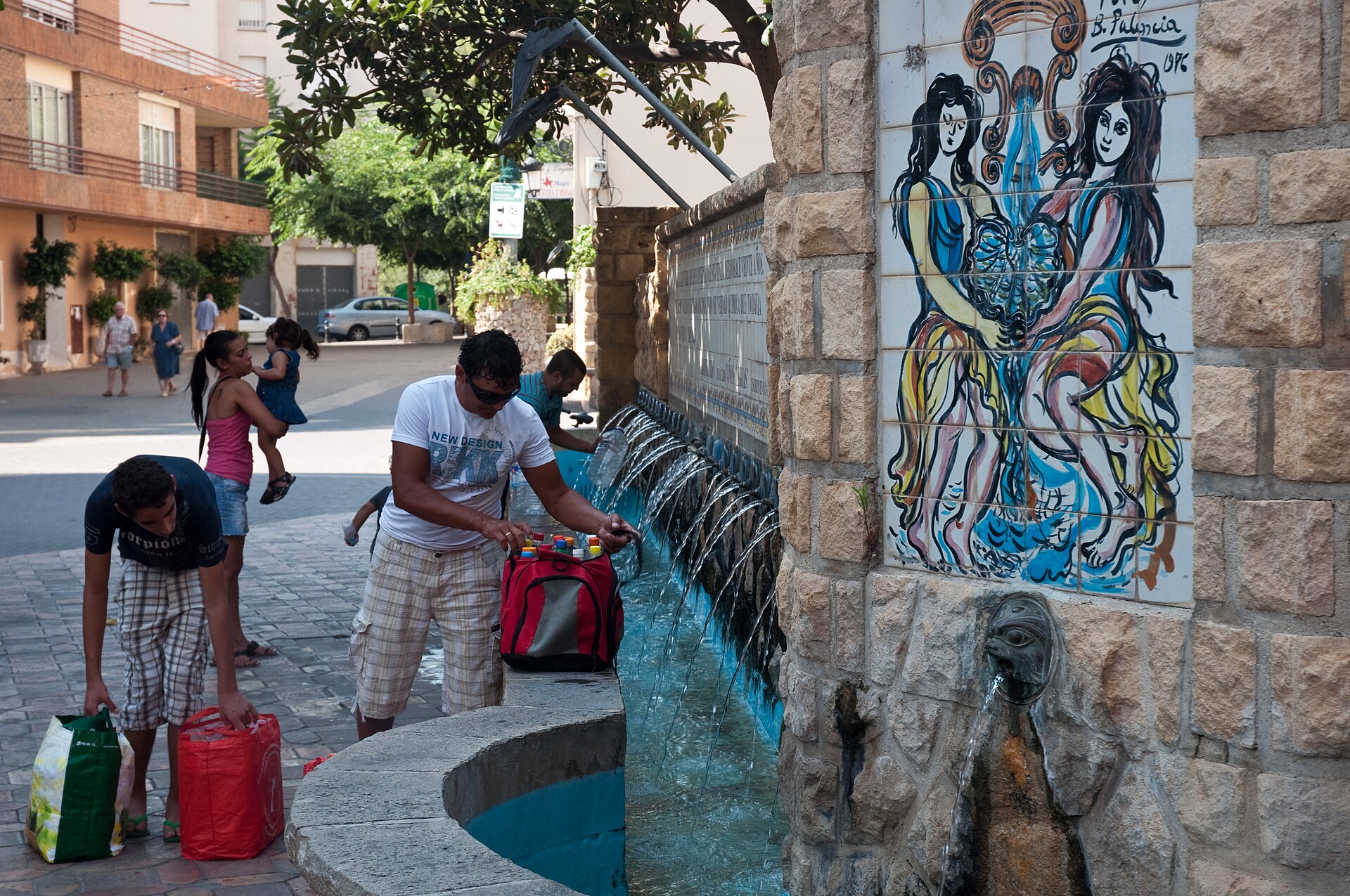 Fuente y plaza de la Puríssima en Polop con personas rellenando garrafas