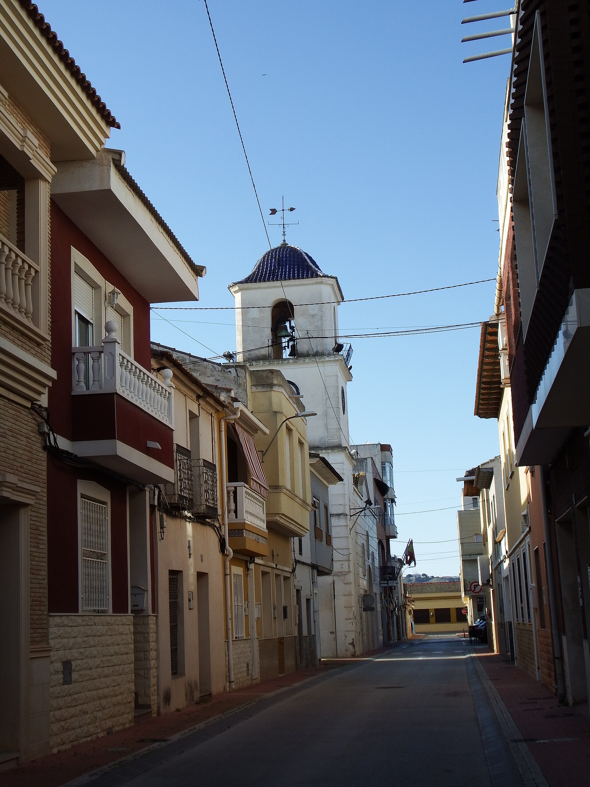 Calle del centro de San Fulgencio con torre de la iglesia al fondo